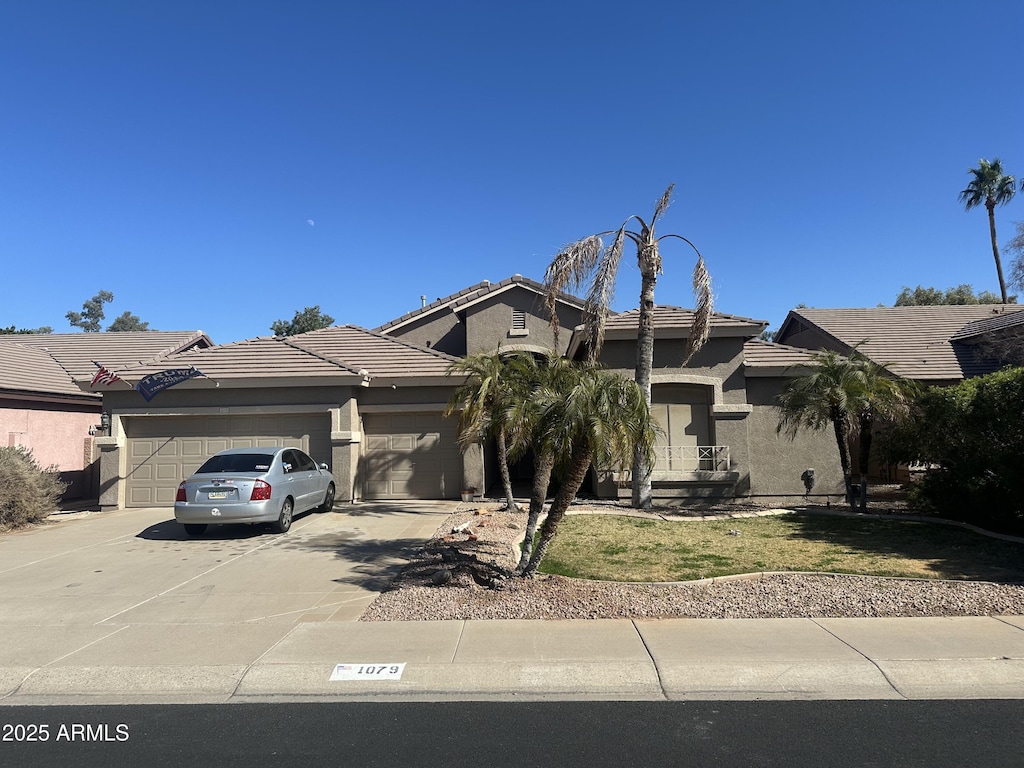 view of front of property with a tile roof, concrete driveway, a garage, and stucco siding