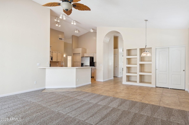 5010 W Ivanhoe St, Chandler, AZ 85226 - unfurnished living room featuring light colored carpet, ceiling fan, arched walkways, light tile patterned floors, and built in shelves