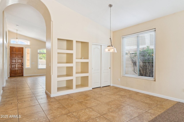 5010 W Ivanhoe St, Chandler, AZ 85226 - empty room featuring vaulted ceiling, built in shelves, arched walkways, baseboards, and light tile patterned floors