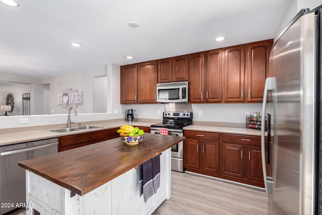 kitchen with light hardwood / wood-style floors, appliances with stainless steel finishes, sink, and butcher block counters