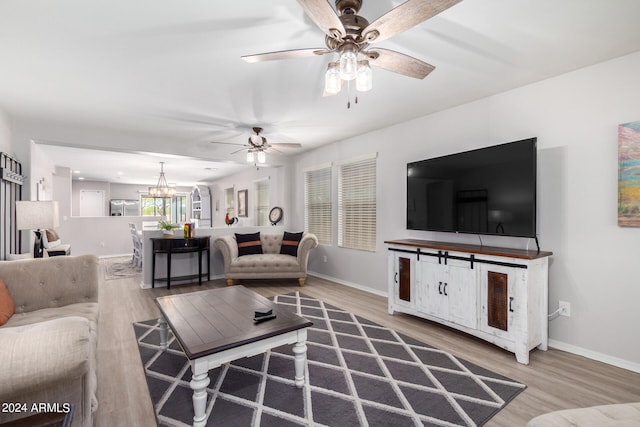 living room with ceiling fan with notable chandelier and hardwood / wood-style flooring