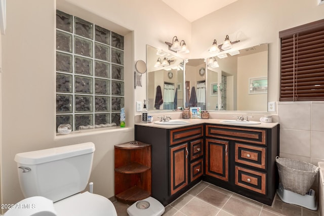 bathroom featuring toilet, a sink, tile walls, and tile patterned floors