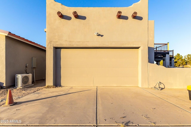 exterior space with a garage, ac unit, and stucco siding