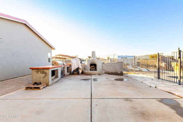 view of patio / terrace featuring exterior kitchen, fence, and an outdoor fireplace