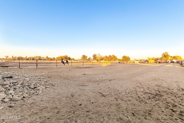 view of yard featuring an enclosed area, a rural view, and fence