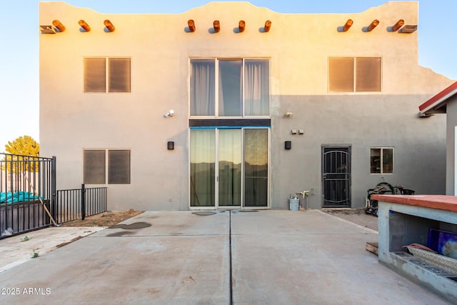 back of property with stucco siding, a patio, and fence