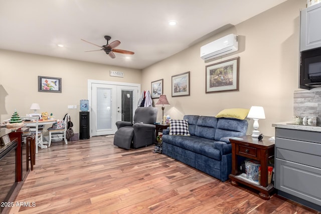 living room featuring light wood finished floors, ceiling fan, a wall mounted air conditioner, french doors, and recessed lighting