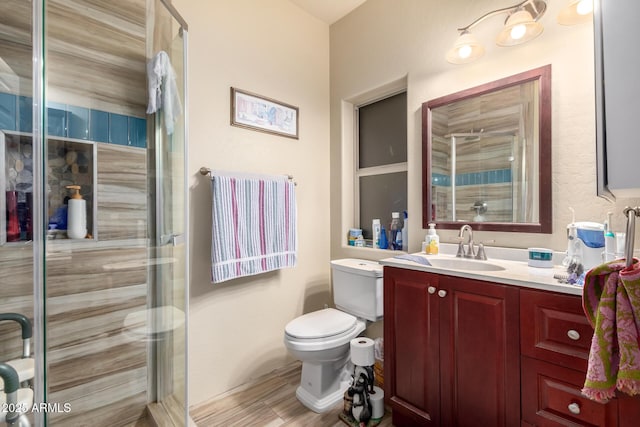 bathroom featuring wood finished floors, a shower stall, toilet, and vanity