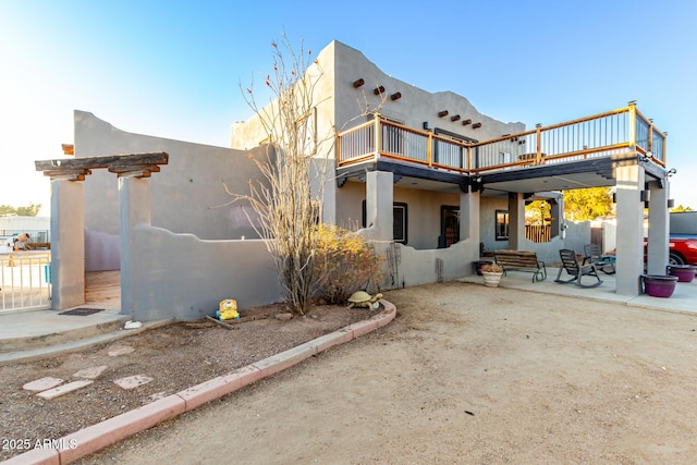 rear view of property with a patio area, fence, and stucco siding