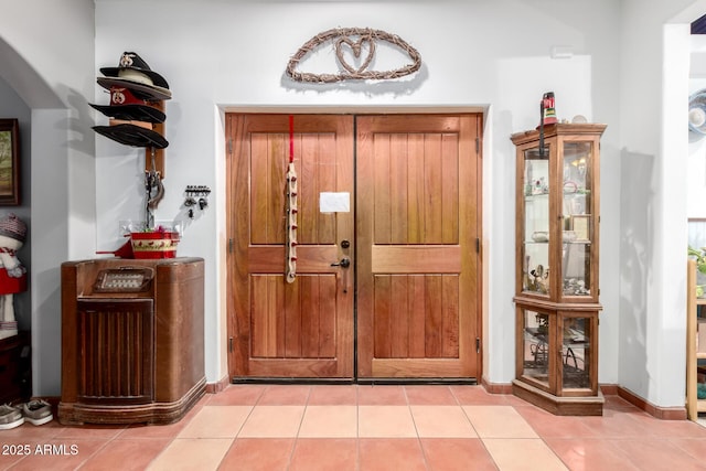 foyer entrance with light tile patterned floors and baseboards