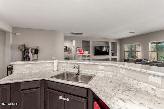 kitchen featuring dark brown cabinetry, sink, and built in features