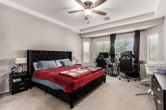 bedroom with a raised ceiling, light carpet, and ceiling fan