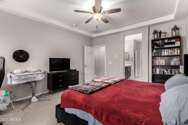 carpeted bedroom featuring ceiling fan, connected bathroom, and a tray ceiling