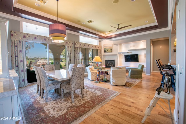 dining area featuring ceiling fan, a raised ceiling, ornamental molding, and light wood-type flooring