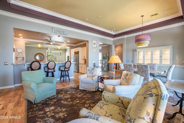 living room with light hardwood / wood-style floors, ornamental molding, and ceiling fan