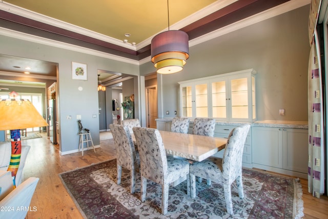 dining space with ornamental molding and light hardwood / wood-style floors