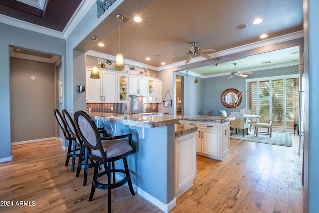 kitchen featuring white cabinetry, a breakfast bar, light hardwood / wood-style flooring, and kitchen peninsula