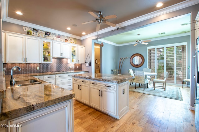 kitchen featuring a kitchen island, white cabinetry, light wood-type flooring, ornamental molding, and sink