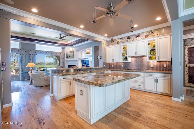 kitchen featuring ornamental molding, light hardwood / wood-style flooring, white cabinetry, and light stone counters