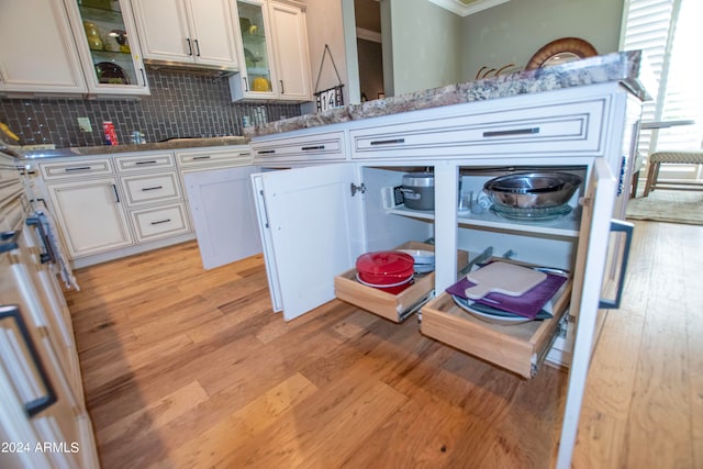 kitchen featuring white cabinets, tasteful backsplash, light stone counters, and light wood-type flooring