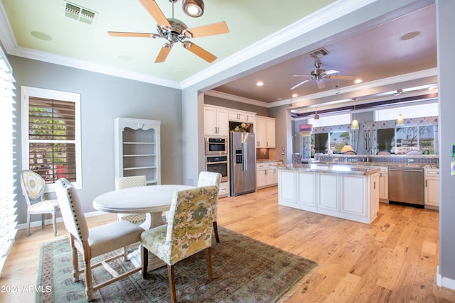 dining space with sink, crown molding, light wood-type flooring, and ceiling fan