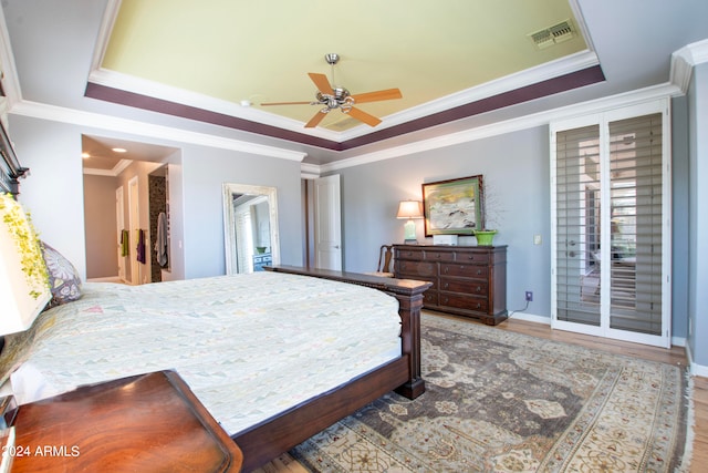 bedroom featuring a raised ceiling, wood-type flooring, and ceiling fan