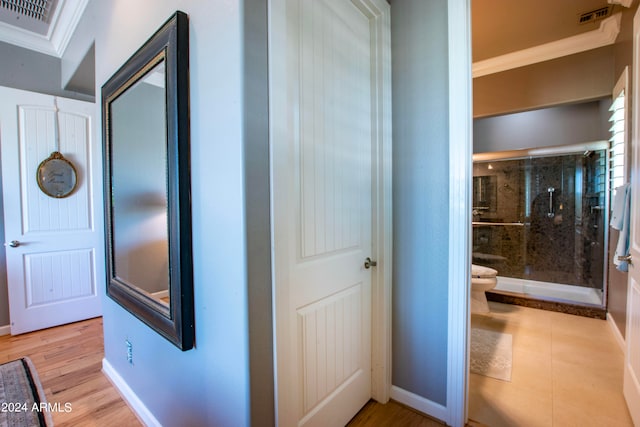 hallway with ornamental molding and light wood-type flooring