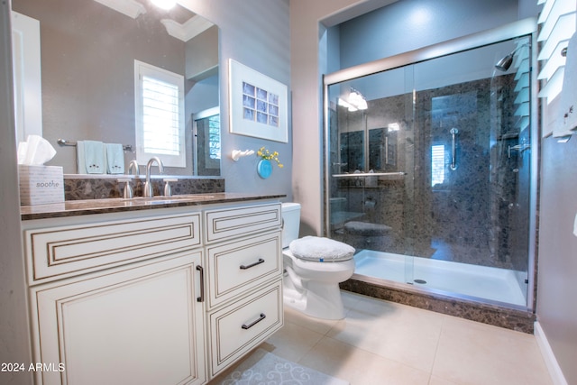 bathroom featuring toilet, vanity, tile patterned floors, and a shower with door