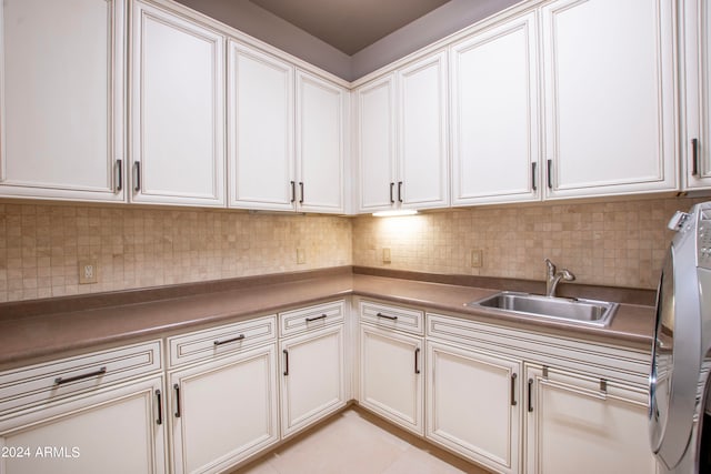 laundry room featuring cabinets, washer and dryer, sink, and light tile patterned floors