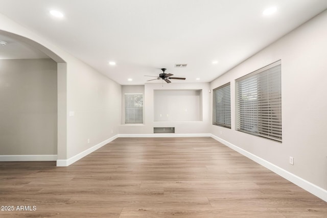 unfurnished living room featuring light wood finished floors, baseboards, visible vents, and a ceiling fan