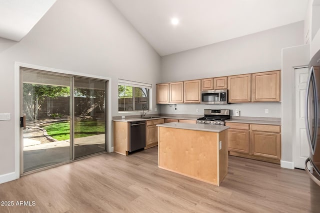 kitchen with a kitchen island, stainless steel appliances, light countertops, light wood-type flooring, and a sink