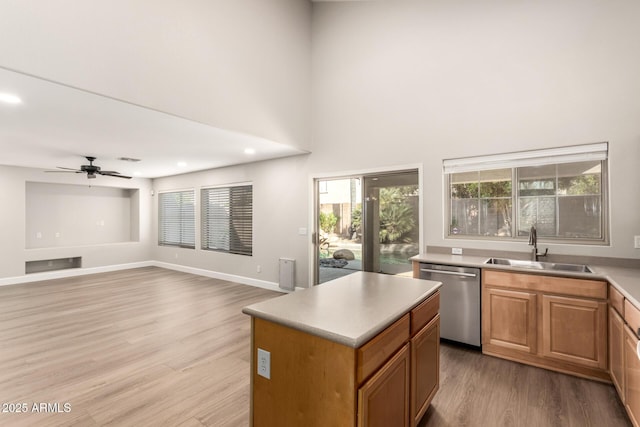 kitchen featuring a center island, a sink, light wood-type flooring, dishwasher, and baseboards