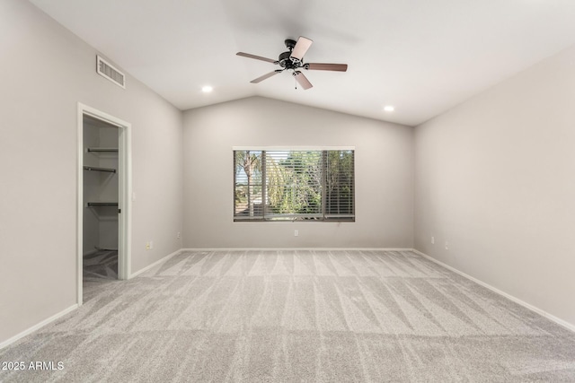 spare room featuring vaulted ceiling, light carpet, visible vents, and baseboards