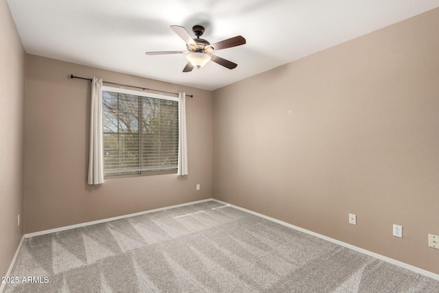 carpeted spare room featuring ceiling fan and baseboards