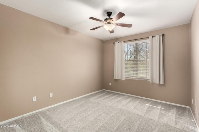 carpeted spare room with a ceiling fan and baseboards