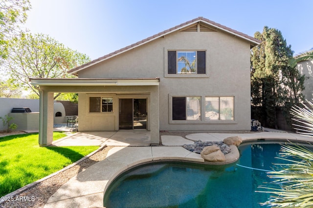 back of house featuring a fenced in pool, a patio, a lawn, and stucco siding