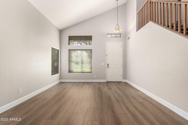 foyer entrance featuring high vaulted ceiling, baseboards, and wood finished floors