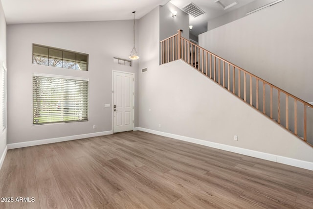 entrance foyer featuring visible vents, wood finished floors, high vaulted ceiling, baseboards, and stairs