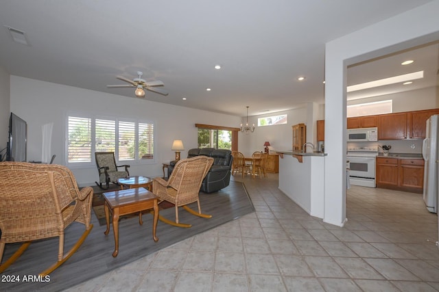 tiled dining space featuring ceiling fan with notable chandelier and sink