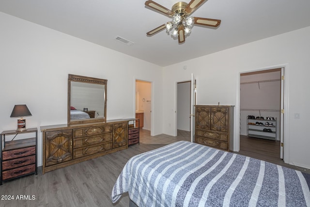 bedroom featuring ensuite bath, light wood-type flooring, a walk in closet, a closet, and ceiling fan