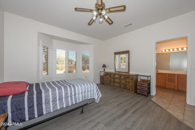 bedroom featuring ensuite bath, hardwood / wood-style floors, and ceiling fan