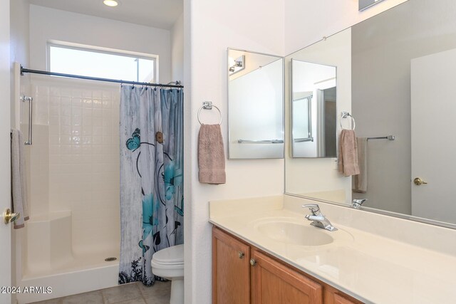 bathroom with a shower with shower curtain, tile patterned flooring, toilet, and vanity