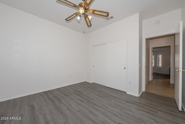 unfurnished bedroom featuring dark wood-type flooring, ceiling fan, and a closet