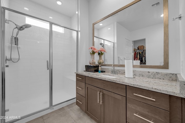 bathroom with tile patterned flooring, vanity, and walk in shower