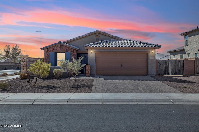 view of front facade featuring decorative driveway, a tiled roof, an attached garage, and stucco siding