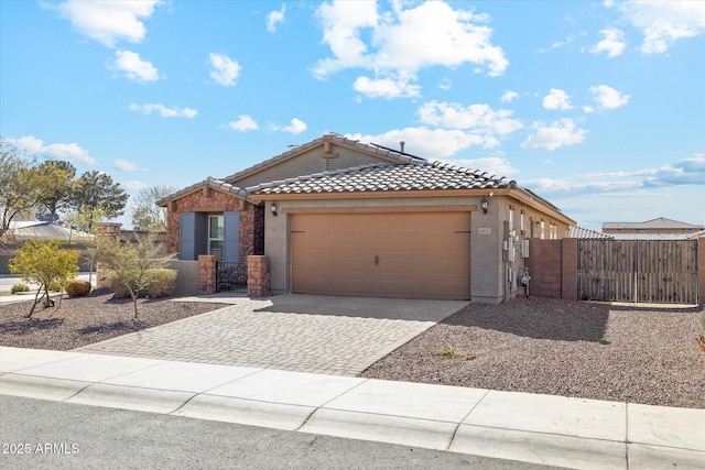 view of front of home featuring an attached garage, fence, a tiled roof, decorative driveway, and stucco siding