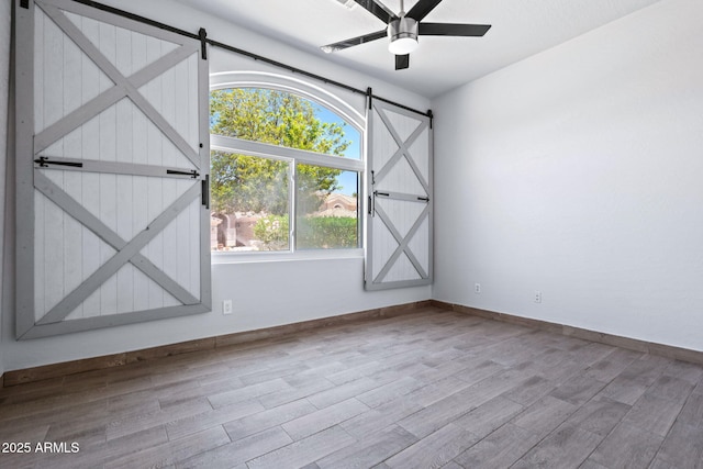 7911 E Posada Ave, Mesa, AZ 85212 - empty room featuring a barn door, wood finished floors, and ceiling fan