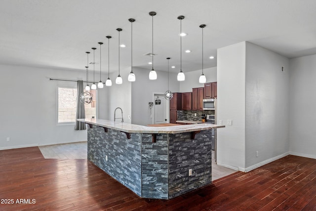 7911 E Posada Ave, Mesa, AZ 85212 - kitchen with stainless steel microwave, light wood-style floors, a breakfast bar, a large island, and recessed lighting