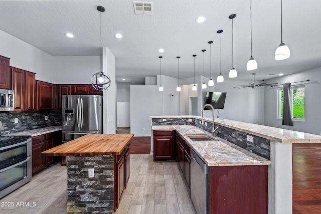 7911 E Posada Ave, Mesa, AZ 85212 - kitchen featuring appliances with stainless steel finishes, a large island, decorative backsplash, butcher block counters, and light wood finished floors