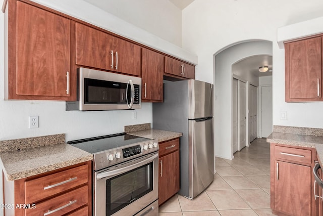 kitchen featuring stainless steel appliances, light tile patterned floors, and light stone counters